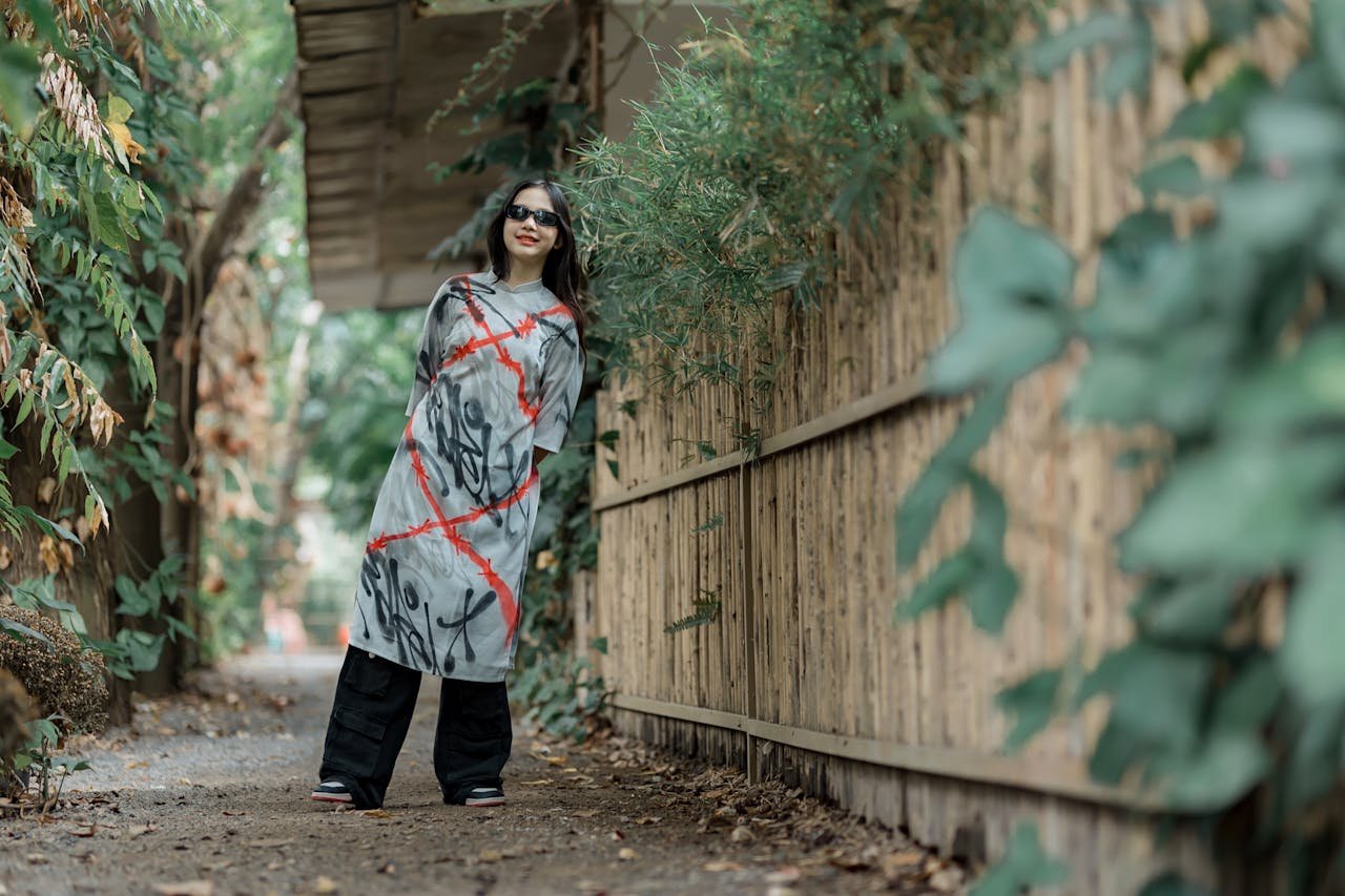 Crafting Captivating Headlines: Your awesome post title goes here Fashionable woman in graffiti dress stands stylishly outdoors in a leafy path.