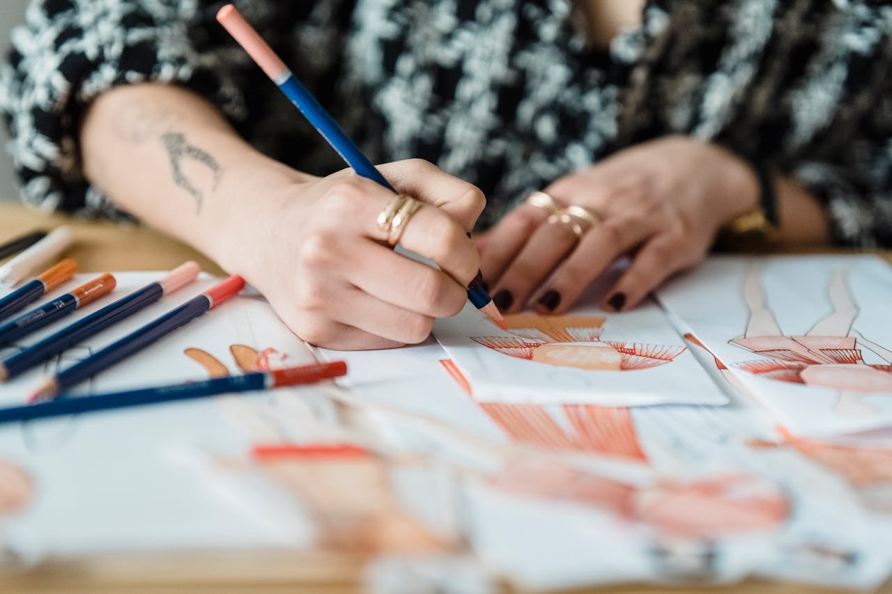 Mastering the First Impression: Your intriguing post title goes here Crop anonymous tattooed female designer coloring apparel illustration on human figure on paper sheet while working at desk