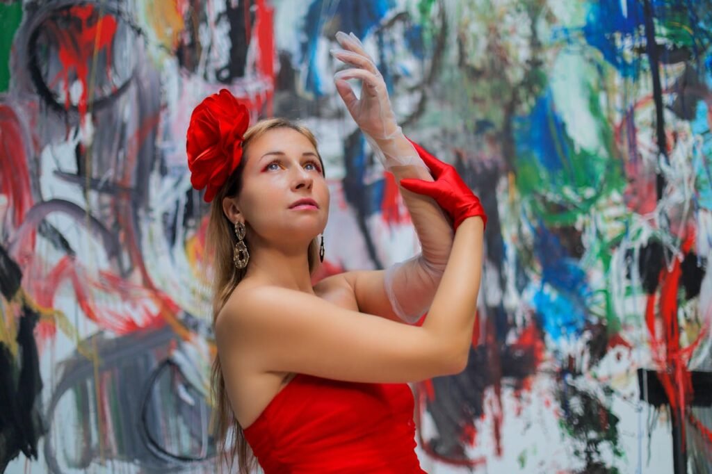 Elegant woman in red dress posing against a colorful abstract backdrop.